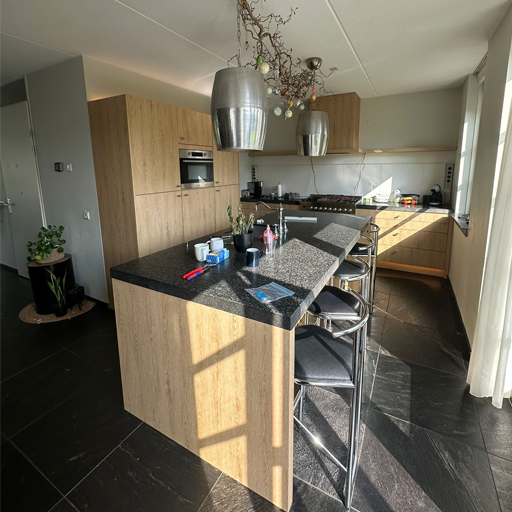 Keukenwrap Noordwolde: donkere keuken vernieuwd met NF34 Beige Golden Oak. De indelingen in de fronten zijn weggewrapt, wat zorgt voor een strak, warm en modern eindresultaat met oog voor detail.