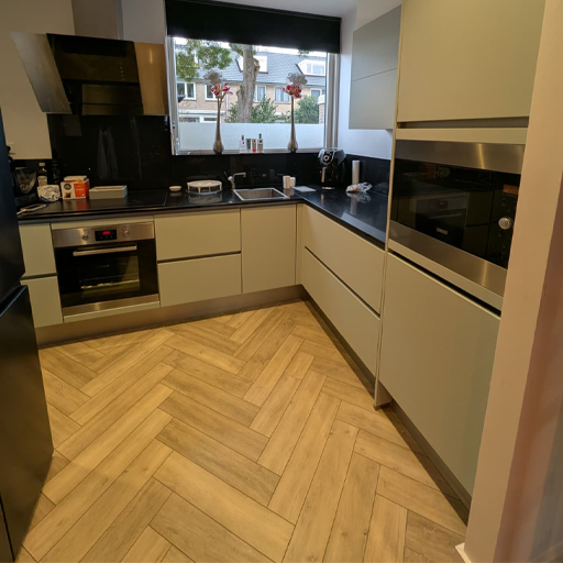 Keukenwrap in Deventer waarbij de hoogglans witte keuken is vernieuwd met NH21 Soft Green. De matte uitstraling brengt rust en warmte in de ruimte en vormt een mooi contrast met het donkere werkblad.