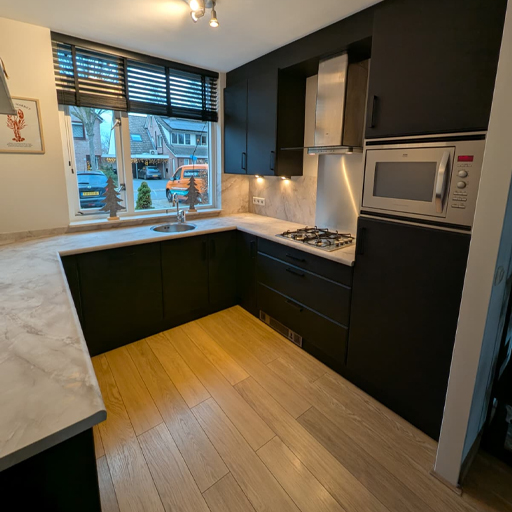 In Schalkhaar is de keuken vernieuwd door de fronten te wrappen in K1 Mat Black Velvet Grain en het werkblad en een deel van de achterwand uit te voeren in NE70 Mat Beige Marble. Dit zorgt voor een strak en modern geheel.